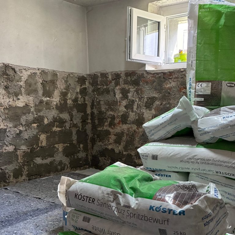 Kernsanierung Rohbau mit freiliegendem Ziegelmauerwerk und Baustellenausrüstung im Hintergrund.